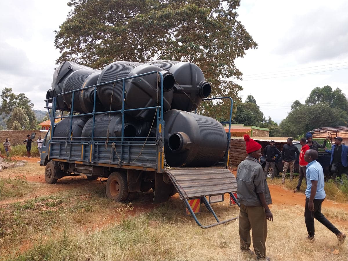 A lorry loaded with black water tanks at a rural Kenyan delivery site